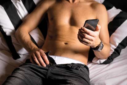 man looking at phone pulling his pants down